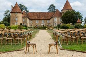 Hochzeitszeremonie vor dem Hintergrund eines alten Schlosses. Reihen von Holzstühlen für Gäste, die auf dem Rasen im Garten des französischen Schlosses stehen. Schöne Gegend für Hochzeiten, bzw. Open-Air-Feiern.