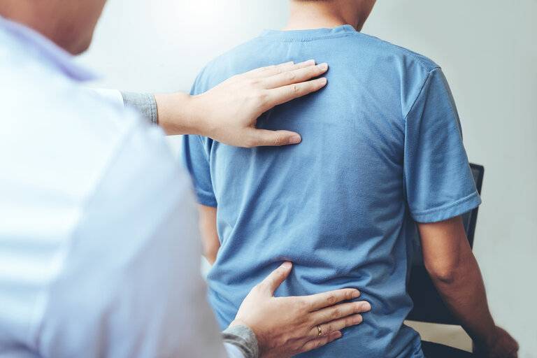 Arzt im Gespräch mit dem Patienten Rückenprobleme Konzept der physikalischen Therapie