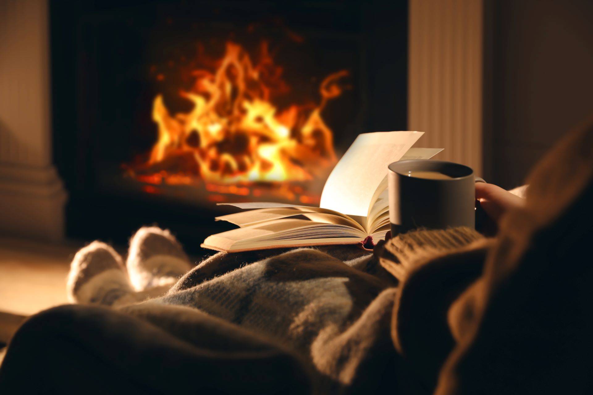 Gemütlicher Abend vor dem Kamin mit Buch und Tee