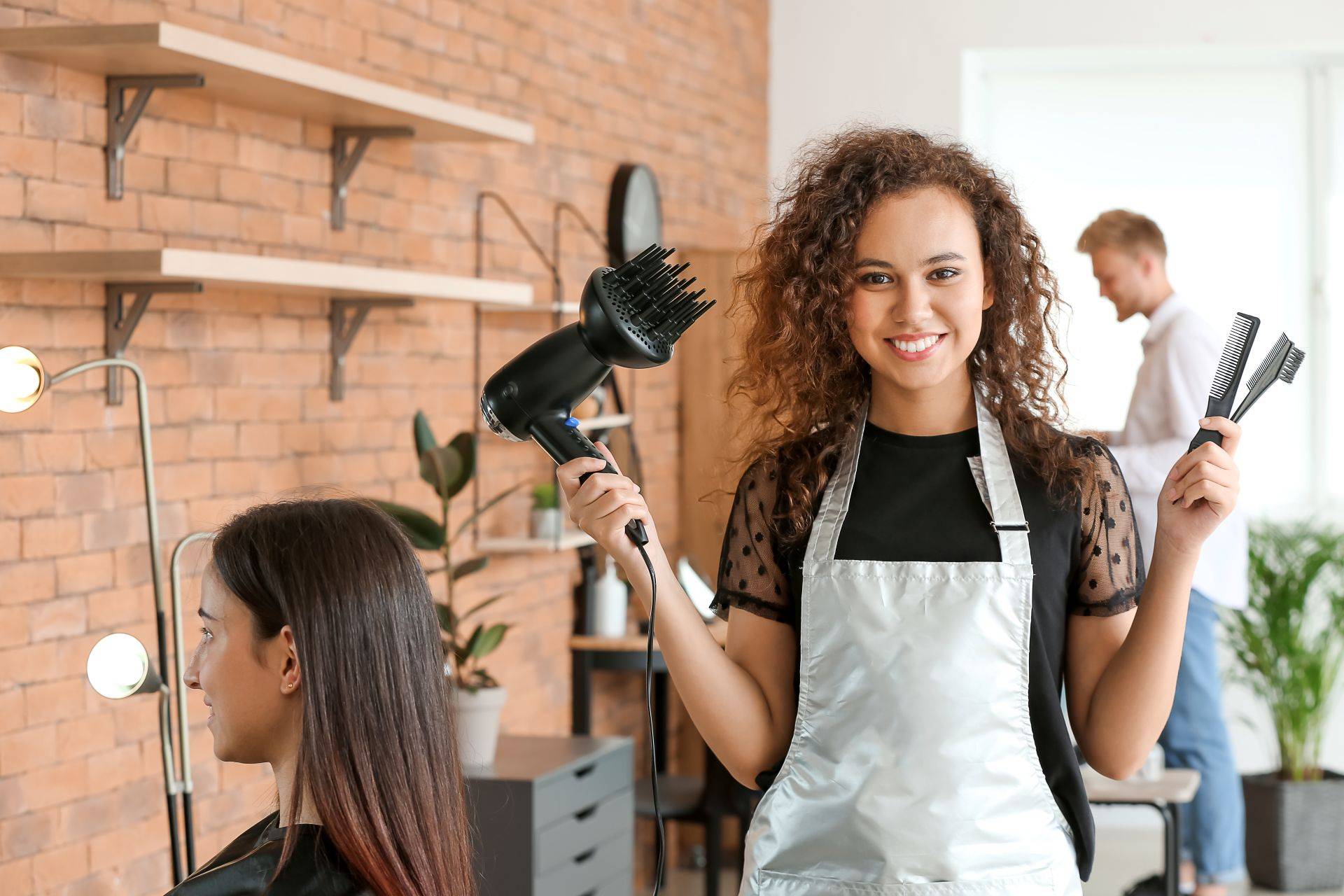 Hairstylist with blow dryer and combs at salon in Göppingen