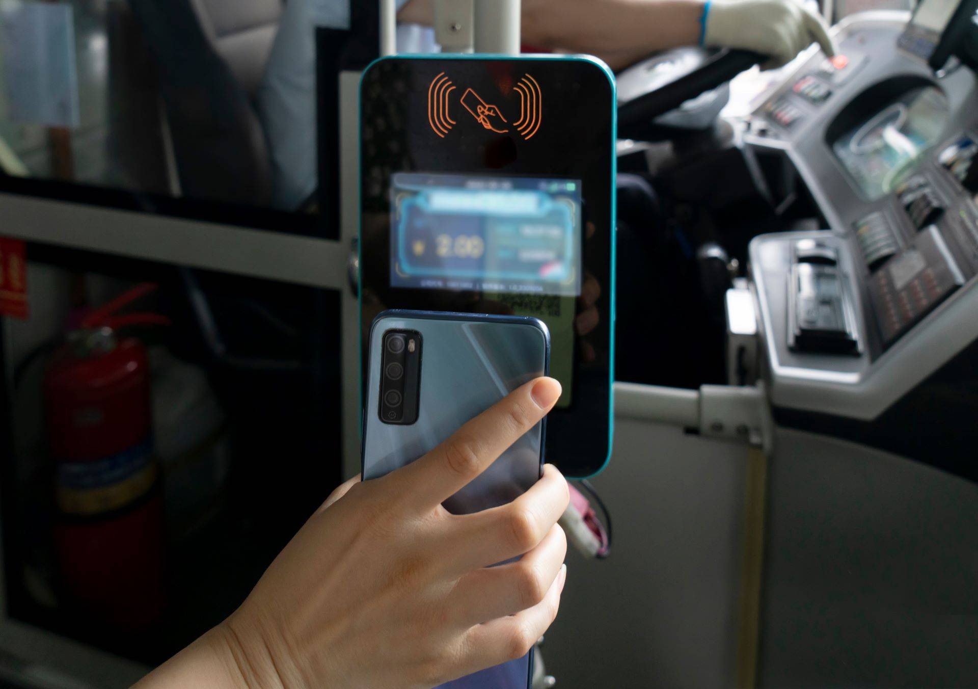 Fahrgast hält Smartphone an kontaktloses Bezahlsystem im Bus.